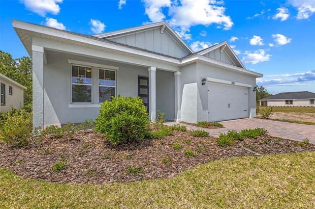 1261 Champions Dr, Daytona Beach, FL 32124 - view of front of house featuring board and batten siding, a garage, a porch, driveway, and stucco siding