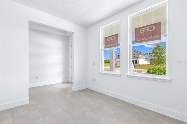 1261 Champions Dr, Daytona Beach, FL 32124 - tiled spare room featuring a textured ceiling and baseboards