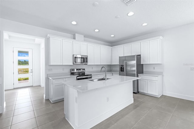 1261 Champions Dr, Daytona Beach, FL 32124 - kitchen featuring appliances with stainless steel finishes, light countertops, a kitchen island with sink, light tile patterned flooring, and recessed lighting