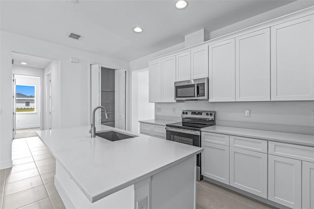 1261 Champions Dr, Daytona Beach, FL 32124 - kitchen with stainless steel appliances, light tile patterned flooring, recessed lighting, a center island with sink, and light countertops
