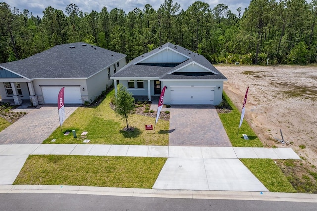 1261 Champions Dr, Daytona Beach, FL 32124 - view of front of house featuring decorative driveway, an attached garage, a front yard, and a forest view