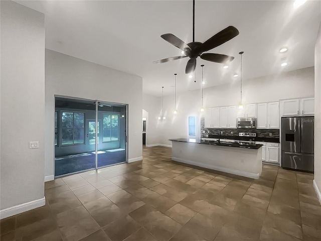 12671 Flatwood Creek Dr, Gibsonton, FL 33534 - kitchen featuring appliances with stainless steel finishes, dark countertops, a towering ceiling, a ceiling fan, and backsplash