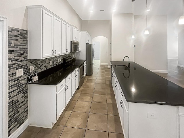 12671 Flatwood Creek Dr, Gibsonton, FL 33534 - kitchen featuring appliances with stainless steel finishes, dark countertops, arched walkways, tasteful backsplash, and white cabinets