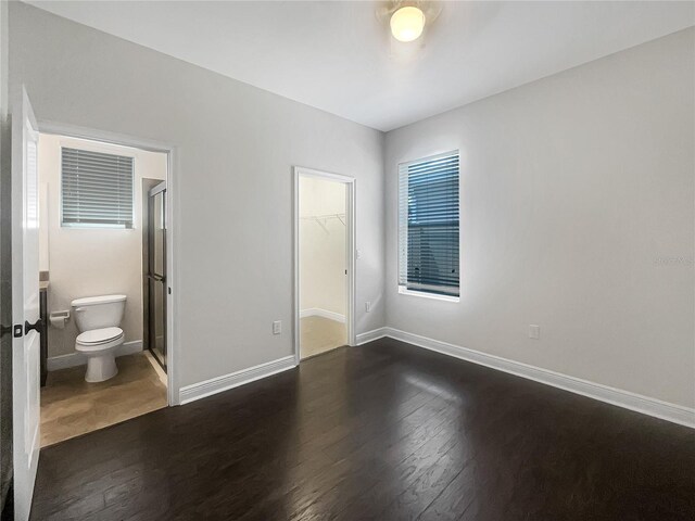 12671 Flatwood Creek Dr, Gibsonton, FL 33534 - unfurnished bedroom with a walk in closet, dark wood finished floors, and connected bathroom