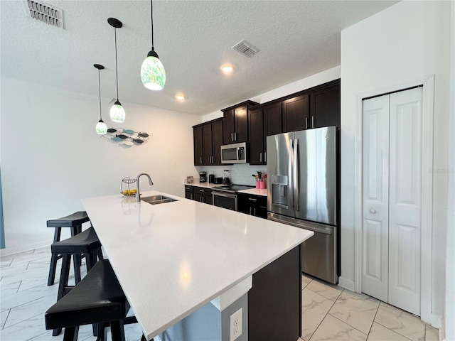 4192 Paragraph Dr, Kissimmee, FL 34746 - kitchen featuring stainless steel appliances, light marble finish flooring, light countertops, a center island with sink, and a breakfast bar
