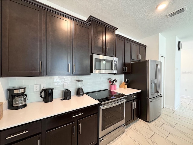4192 Paragraph Dr, Kissimmee, FL 34746 - kitchen with appliances with stainless steel finishes, light countertops, a textured ceiling, light marble finish floors, and tasteful backsplash