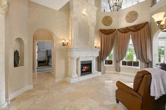 11209 Macaw Ct, Windermere, FL 34786 - living area featuring a towering ceiling, marble tiled flooring, a chandelier, a warm lit fireplace, and arched walkways