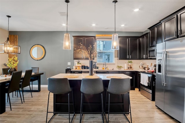 6992 Dilly Lake Ave, Groveland, FL 34736 - kitchen featuring stainless steel appliances, light countertops, light wood-style flooring, a center island, and a kitchen bar