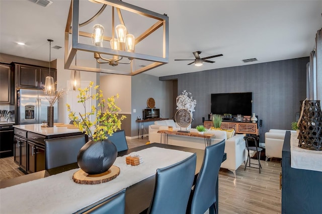 6992 Dilly Lake Ave, Groveland, FL 34736 - dining room featuring wallpapered walls, an accent wall, a ceiling fan, a chandelier, and light wood-style flooring