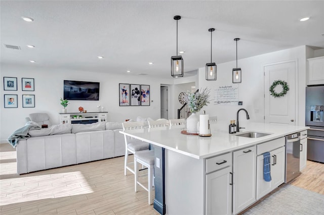 4477 Renly Ln, Clermont, FL 34711 - kitchen with appliances with stainless steel finishes, light wood-style floors, a center island with sink, open floor plan, and light countertops