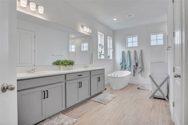 4477 Renly Ln, Clermont, FL 34711 - full bathroom featuring double vanity, a freestanding bath, wood finished floors, a shower, and recessed lighting