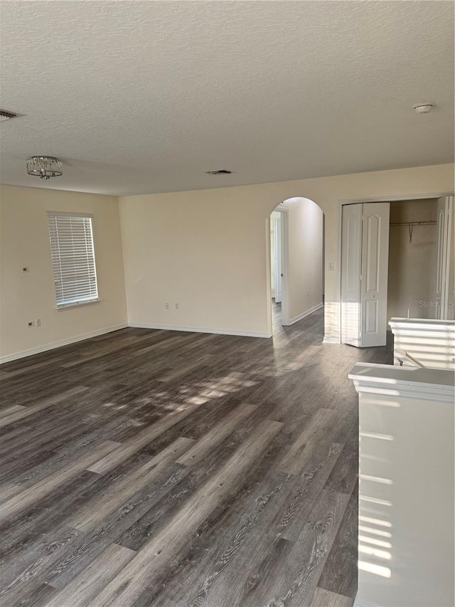 1954 Marabou Dr, Davenport, FL 33896 - unfurnished room featuring dark wood-type flooring, arched walkways, a textured ceiling, and a smoke detector