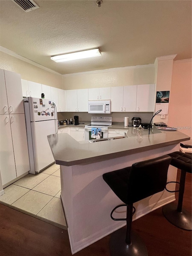 3593 Conroy Rd Unit 416, Orlando, FL 32839 - kitchen with crown molding, a peninsula, white appliances, white cabinetry, and a kitchen breakfast bar