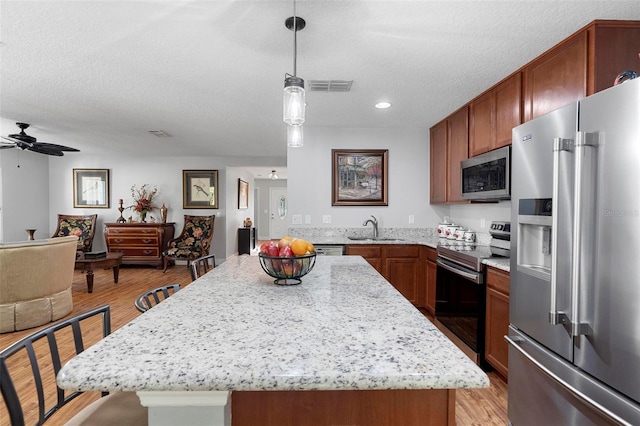 43 Pergola Pl, Ormond Beach, FL 32174 - kitchen featuring appliances with stainless steel finishes, ceiling fan, light wood finished floors, light stone counters, and a textured ceiling