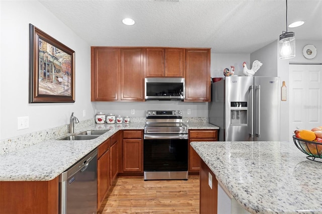 43 Pergola Pl, Ormond Beach, FL 32174 - kitchen featuring appliances with stainless steel finishes, light wood-type flooring, light stone counters, brown cabinetry, and a textured ceiling