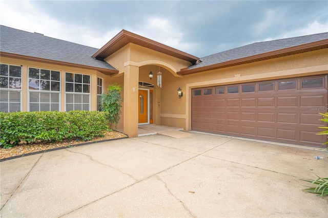 10642 Masters Dr, Clermont, FL 34711 - doorway to property with roof with shingles, driveway, stucco siding, and a garage
