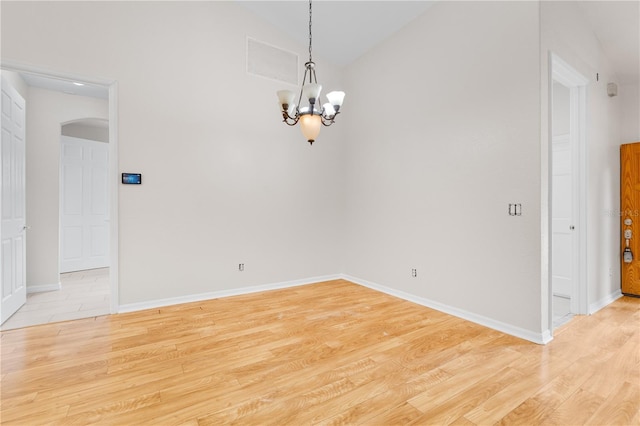 10642 Masters Dr, Clermont, FL 34711 - empty room featuring arched walkways, a chandelier, light wood finished floors, and lofted ceiling