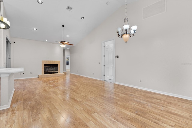 10642 Masters Dr, Clermont, FL 34711 - unfurnished living room with a ceiling fan, a tiled fireplace, high vaulted ceiling, light wood-style flooring, and a chandelier