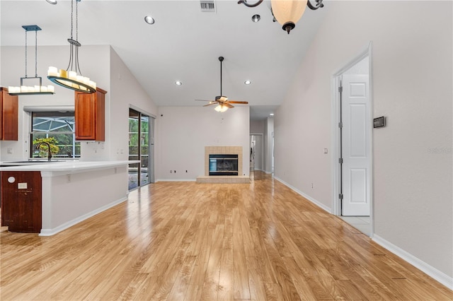 10642 Masters Dr, Clermont, FL 34711 - unfurnished living room featuring light wood-style flooring, a ceiling fan, lofted ceiling, a tile fireplace, and recessed lighting