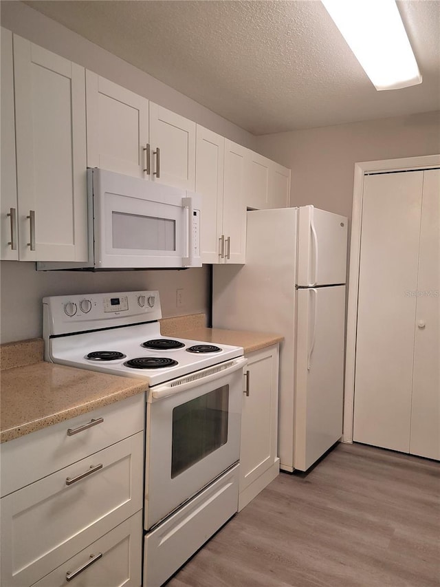 4400 Thornbriar Ln Unit A103, Orlando, FL 32822 - kitchen featuring white appliances, light wood-style floors, white cabinets, a textured ceiling, and light stone counters
