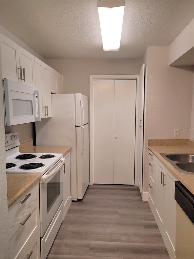4400 Thornbriar Ln Unit A103, Orlando, FL 32822 - kitchen with white appliances, a textured ceiling, white cabinets, light countertops, and light wood finished floors