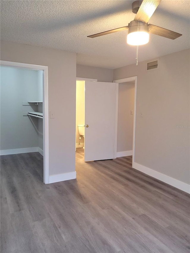 4400 Thornbriar Ln Unit A103, Orlando, FL 32822 - unfurnished bedroom featuring wood finished floors, a spacious closet, a ceiling fan, and a textured ceiling
