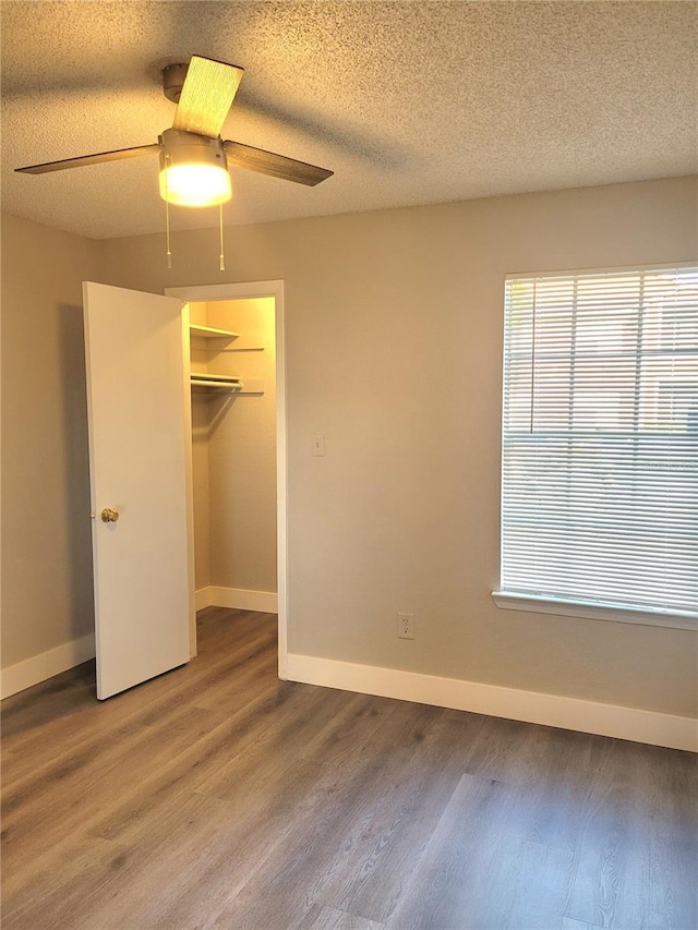 4400 Thornbriar Ln Unit A103, Orlando, FL 32822 - unfurnished bedroom with wood finished floors, ceiling fan, a textured ceiling, and a walk in closet