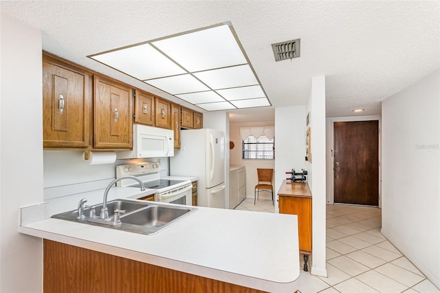 4570 Ocean Beach Blvd Unit 226, Cocoa Beach, FL 32931 - kitchen with light tile patterned floors, white appliances, brown cabinetry, independent washer and dryer, and light countertops