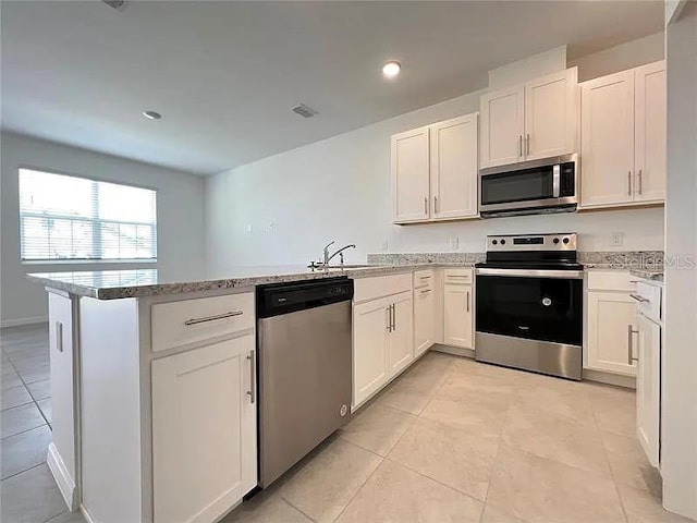 2343 Garden Belle Dr, Clermont, FL 34711 - kitchen with a peninsula, stainless steel appliances, white cabinets, light tile patterned floors, and light stone counters
