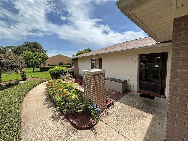 8131 Braddock Cir Unit 1, Port Richey, FL 34668 - property entrance with roof with shingles, stucco siding, a lawn, and brick siding