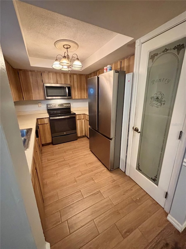 8131 Braddock Cir Unit 1, Port Richey, FL 34668 - kitchen with a raised ceiling, a textured ceiling, appliances with stainless steel finishes, light countertops, and light wood-style flooring