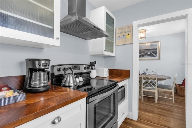 2790 Ocean Shore Blvd Unit 8N, Ormond Beach, FL 32176 - kitchen featuring butcher block countertops, stainless steel appliances, wall chimney range hood, and glass insert cabinets