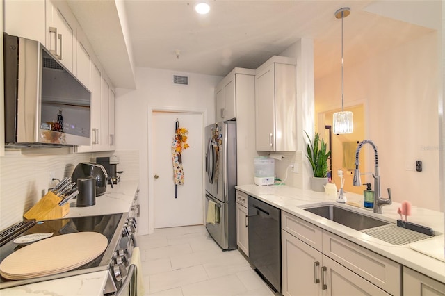 5554 Metrowest Blvd Unit 305, Orlando, FL 32811 - kitchen featuring stainless steel appliances, light stone countertops, decorative light fixtures, backsplash, and white cabinetry