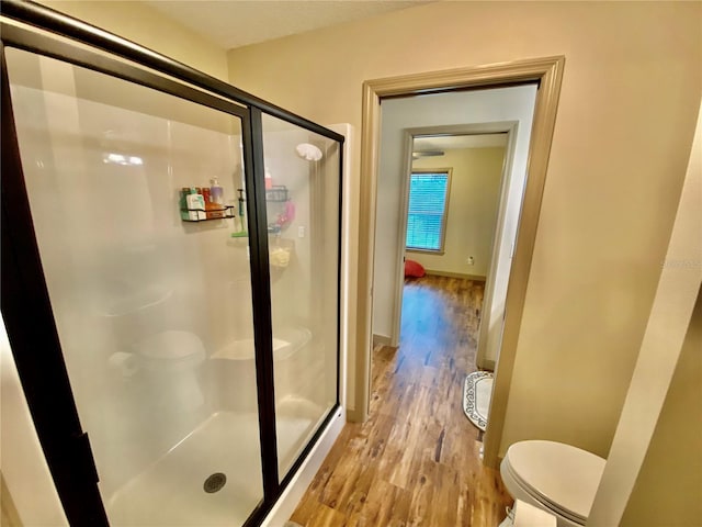 bathroom featuring an enclosed shower, toilet, and wood-type flooring