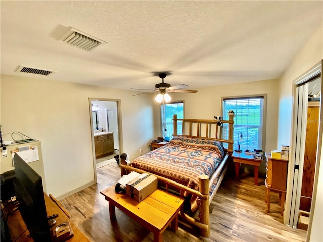 bedroom with connected bathroom, a textured ceiling, ceiling fan, and hardwood / wood-style flooring