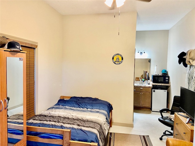 bedroom with light carpet, ensuite bath, ceiling fan, and refrigerator