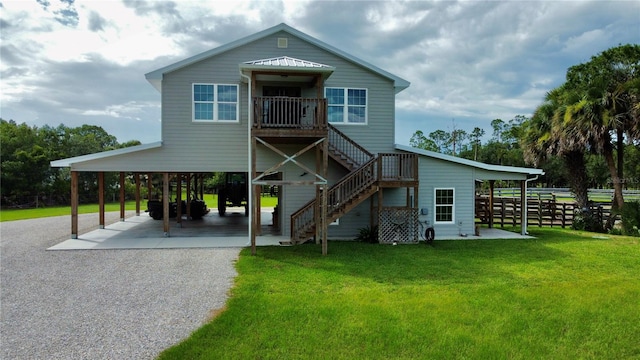 back of property with a carport, a lawn, and a patio area