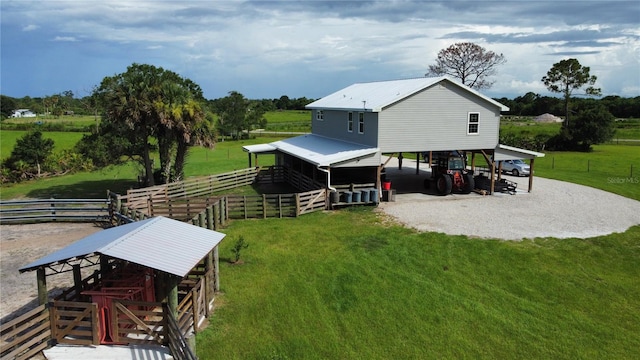 back of property featuring a lawn, a rural view, and a carport