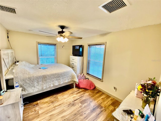 bedroom with ceiling fan, multiple windows, and light wood-type flooring