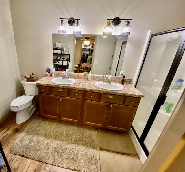 bathroom with walk in shower, hardwood / wood-style floors, double vanity, and toilet