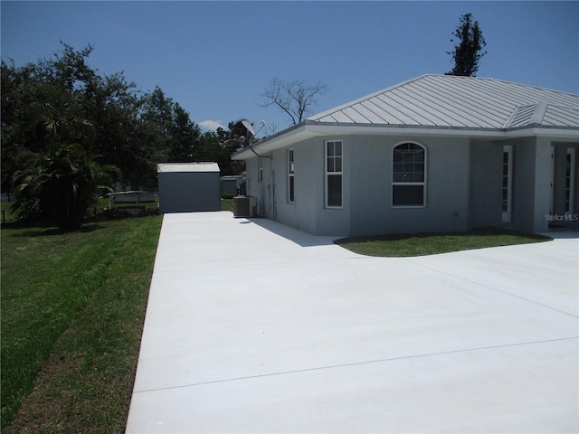 view of side of home featuring a lawn, a patio area, and a storage unit