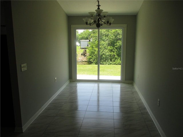 empty room featuring plenty of natural light, a notable chandelier, and light tile floors