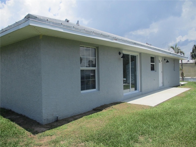 back of property with a lawn and a patio