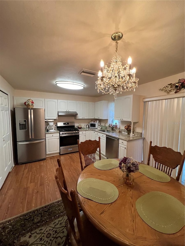 dining space featuring sink, an inviting chandelier, and light hardwood / wood-style flooring