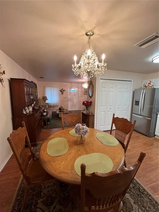 dining room with hardwood / wood-style flooring and an inviting chandelier