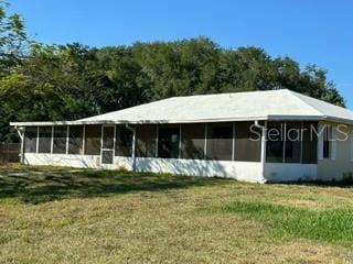 rear view of house with a sunroom and a lawn