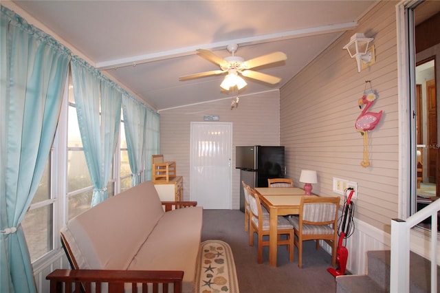 carpeted dining area with ceiling fan and lofted ceiling with beams