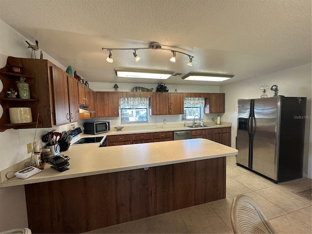 kitchen featuring kitchen peninsula, sink, stainless steel appliances, track lighting, and a textured ceiling