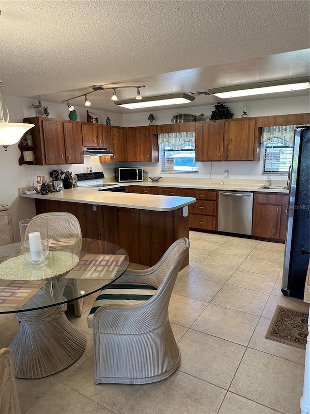 kitchen with a textured ceiling, stainless steel appliances, a healthy amount of sunlight, and track lighting