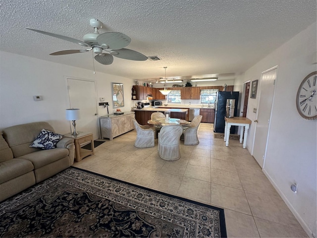 living room featuring a textured ceiling, light tile flooring, and ceiling fan